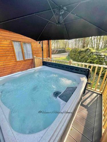 a large outdoor hot tub with an umbrella at Hartland Lodge - White Cross Bay Holiday Park in Windermere