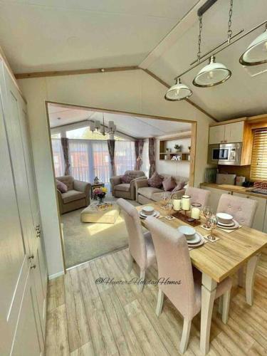 a dining room and living room with a table and chairs at Hartland Lodge - White Cross Bay Holiday Park in Windermere