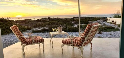 two chairs and a table with wine glasses on a patio at Nieuview Cottage 1 - Cottage 2 - Cottage 3 in Paternoster