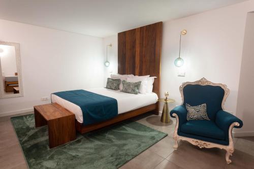 a bedroom with a bed and a blue chair at Casa dos Romeiros in Santa Bárbara