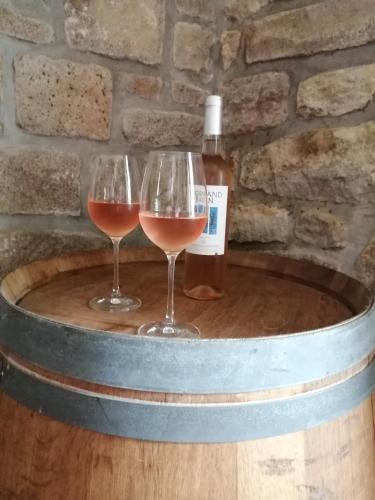 deux verres à vin sur un fût avec une bouteille de vin dans l'établissement Le convivial, à Lohuec