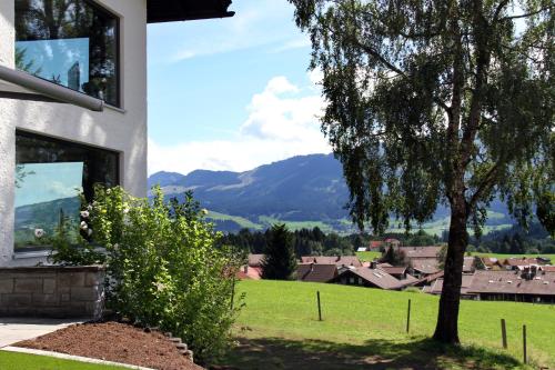 a house with a tree and a green field at Bergzauber Alpin Suites - Skipiste - Private Sauna in Bolsterlang