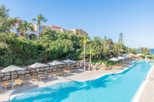 una piscina en un complejo con sillas y sombrillas en Iberostar Selection Andalucia Playa, en Chiclana de la Frontera