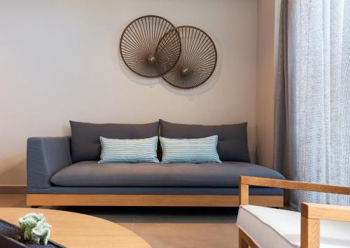 a blue couch in a living room with a fan at Castello Infinity Suites - Adults Only in Agia Pelagia