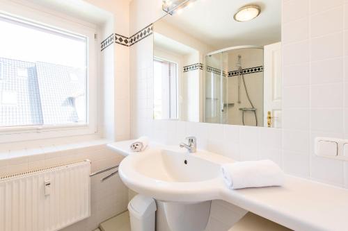 La salle de bains blanche est pourvue d'un lavabo et d'un miroir. dans l'établissement Haus Hauke Whg 8, à Westerland