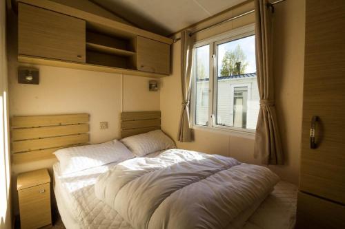 a bed in a small room with a window at Great 6 Berth Caravan By The Beach At California Cliffs In Scratby Ref 50010l in Great Yarmouth