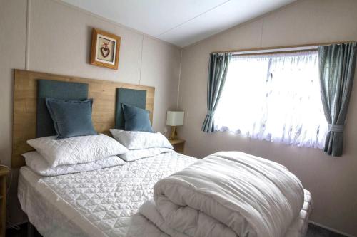 濱海萊斯當的住宿－Beautiful 6 Berth Caravan For Hire At Central Beach Park In Kent Ref 57018b，一间卧室配有一张带白色床单的床和一扇窗户。