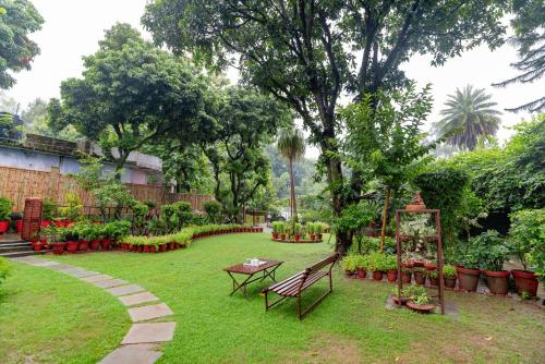 ogród z ławkami i kwiatami na dziedzińcu w obiekcie SaffronStays Doon Garden Villa - near Doon School and Mall Road w mieście Dehradun