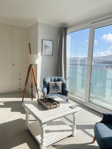 a living room with a blue chair and a table at The Ridge in Menai Bridge