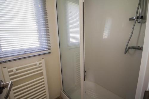 a glass shower door in a bathroom with a window at Lovely Caravan With Free Wifi Nearby Great Yarmouth Seaside Town Ref 20085bs in Hopton on Sea