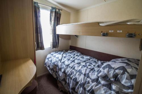 een slaapkamer met een stapelbed in een kamer bij 6 Berth Caravan With Decking At Kessingland Beach In Suffolk Ref 90045sg in Benacre