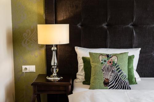 a bedroom with a bed with a zebra pillow and a lamp at Rezydencja Luxury Hotel Bytom Piekary Śląskie in Piekary Śląskie