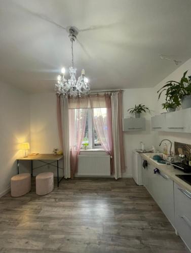 a kitchen with a chandelier and a table and a window at Przytulny apartament na Podgórzu in Kraków