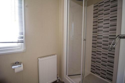 a bathroom with a shower and a toilet and a window at Beautiful 6 Berth Caravan At Suffolk Sands Holiday Park Ref 45010mv in Felixstowe