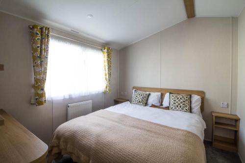 sypialnia z dużym łóżkiem i oknem w obiekcie Lovely 6 Berth Caravan At Coopers Beach Park In Essex Ref 49075p w mieście East Mersea