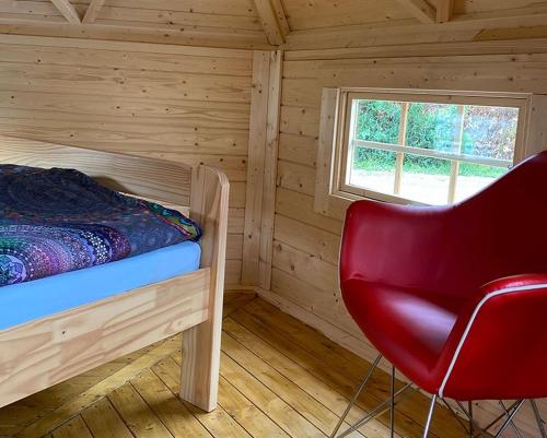 ein Schlafzimmer mit einem Bett und einem roten Stuhl in der Unterkunft Camping Oase Wahlhausen in Wahlhausen