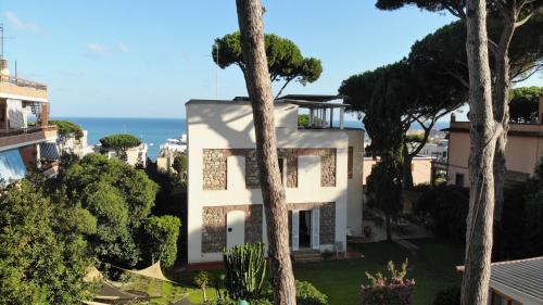 une maison blanche avec des arbres et l'océan en arrière-plan dans l'établissement BUBA BnB SUPERIOR, à Anzio