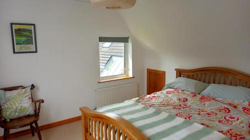 a bedroom with a bed and a chair and a window at Idyllic 3-Bed House minutes from village & beach in Rathmullan