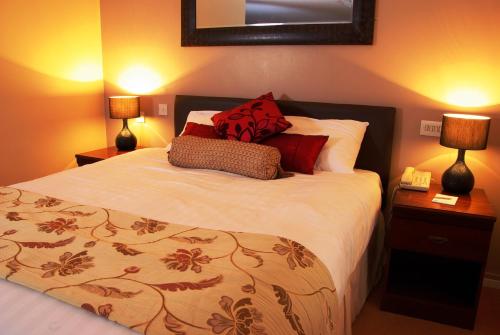 a bedroom with a bed with red pillows and two lamps at Beaufort Park Hotel in Mold