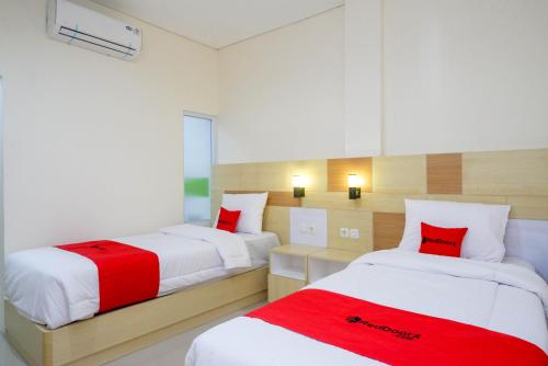 two beds in a room with red and white at RedDoorz Plus near Pasar Gede Solo in Solo