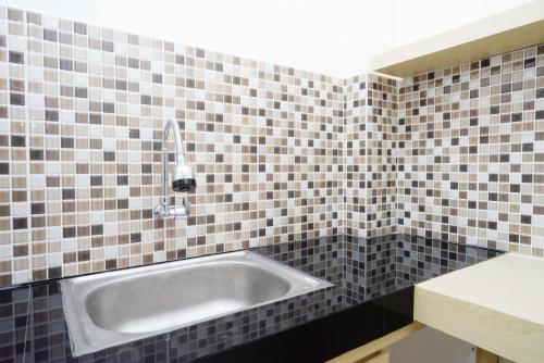 a bathroom with a sink in a tiled wall at RedDoorz Plus near Pasar Gede Solo in Solo