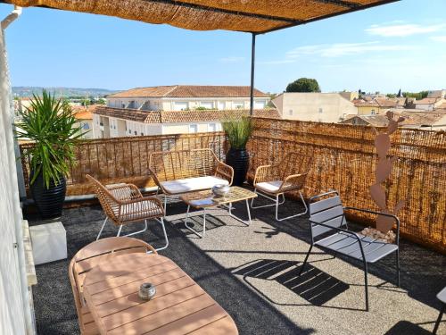 une terrasse avec des chaises, des tables et un parasol dans l'établissement Hôtel Le C - Boutique Hôtel, à Narbonne