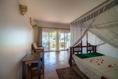 um quarto com uma cama, uma secretária e uma janela em Tanzanite Beach Resort em Nungwi