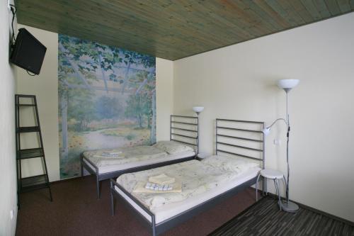 two beds in a room with a painting on the wall at Penzion Rodos - Café in Prague