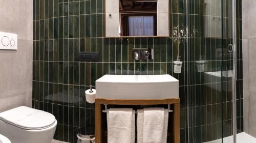 a green tiled bathroom with a sink and a toilet at Castel Sant´Angelo Luxury Rooms & Tour in Rome