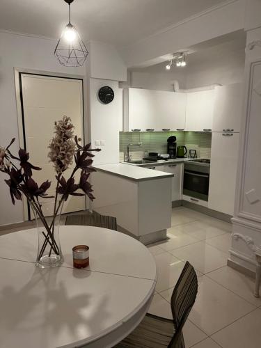 a white kitchen with a table and a vase with flowers at ALKYONI in Athens