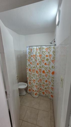 a bathroom with a shower curtain with a toilet at Departamento Don Nico in San José de la Dormida