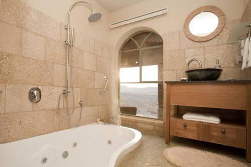 La salle de bains est pourvue d'une baignoire, d'un lavabo et d'un miroir. dans l'établissement Arava Land, à Tzukim