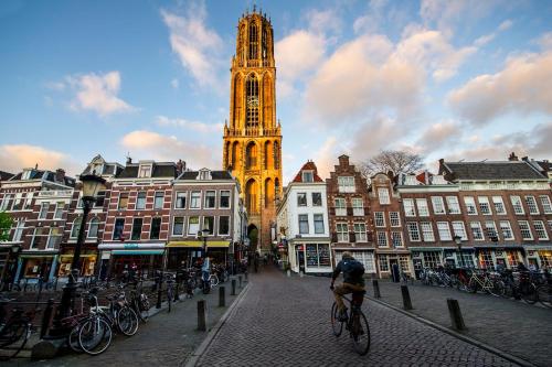 a man riding a bike down a street with a clock tower at Crowne Plaza Utrecht - Central Station by IHG in Utrecht