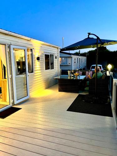 a person sitting on a deck next to a trailer at GOOD SHIP LOLLIPOP LODGE - Birchington-on-Sea - 6 mins drive to Minnis Bay Beach in Kent
