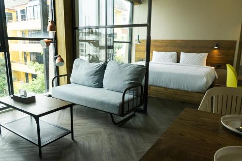 a bedroom with a bed and a couch and a table at karaarom hotel in Bangkok