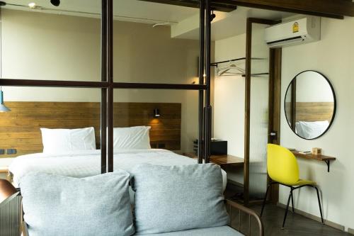 a bedroom with a large bed and a yellow chair at karaarom hotel in Bangkok