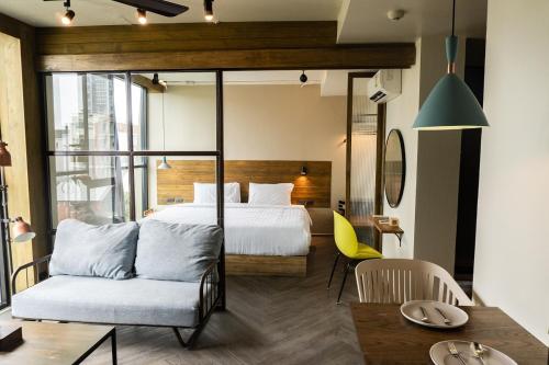 a bedroom with a bed and a couch and a table at karaarom hotel in Bangkok