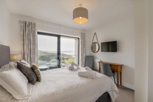 a bedroom with a large bed with a large window at 6 Woolacombe West - Luxury Apartment at Byron Woolacombe, only 4 minute walk to Woolacombe Beach! in Woolacombe