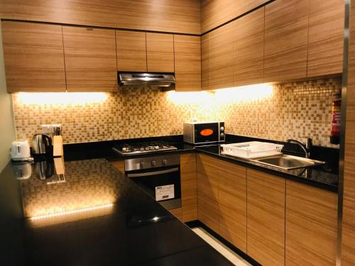 Tulip Al Barsha Hotel Apartment في دبي: مطبخ بدولاب خشبي وموقد ومغسلة