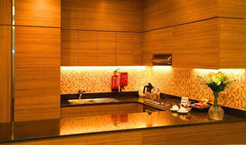 a kitchen with wooden cabinets and a sink and a counter at Tulip Al Barsha Hotel Apartment in Dubai