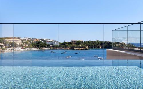 a swimming pool with a view of a body of water at Castello Infinity Suites - Adults Only in Agia Pelagia