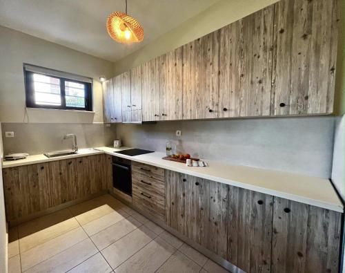 eine Küche mit Holzschränken und einem Waschbecken in der Unterkunft Solis Occasum in Agioi Apostoli