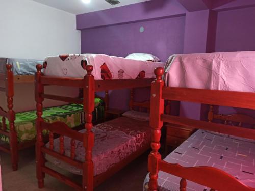 2 Etagenbetten in einem Zimmer mit lila Wänden in der Unterkunft Hospedaje Turisticos. in Libertador General San Martín