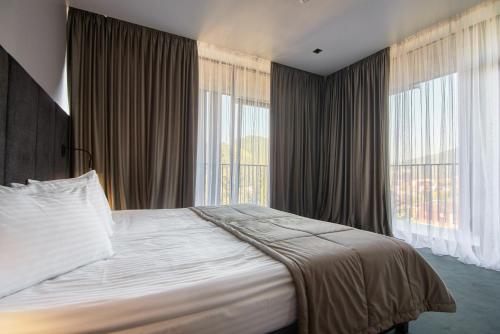 a bedroom with a large bed and large windows at Fomich Residence in Bukovel