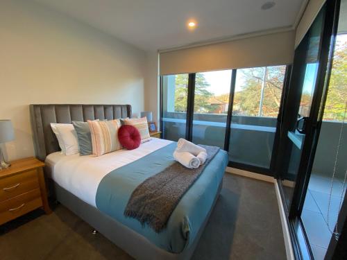 a bedroom with a bed with pillows and a window at New 2 Bed 2 Bath Apt at The Heart of Canberra - 2 Car Spaces in Canberra