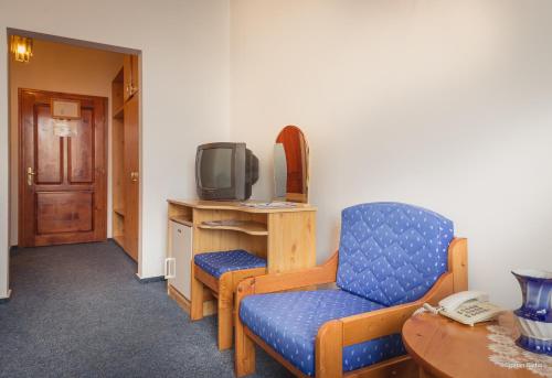 a room with a tv and a chair and a table at Hotel Iris in Tîrnăveni