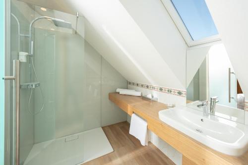 a bathroom with a glass shower and a sink at Hotel Panoramahof Loipersdorf in Jennersdorf
