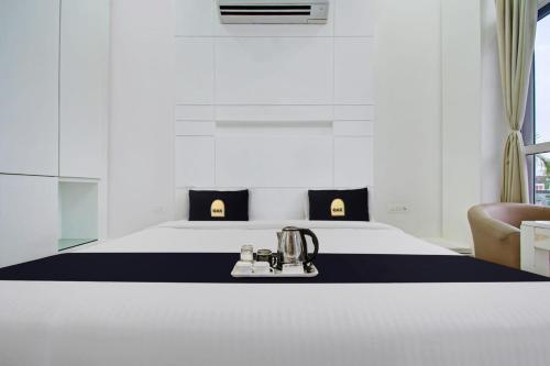 Grande Azure في جايبور: غرفة نوم بسرير ابيض مع مخدات سوداء واصفر