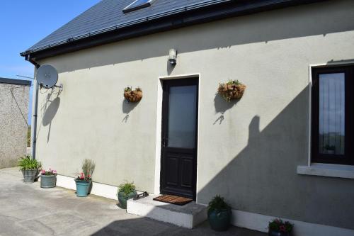 a house with potted plants on the side of it at Cosy two bedroom cottage on the Mullet Peninsula in Ballina