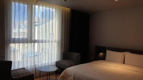 a bedroom with a bed and a table and a window at Jinhae Intercity Hotel in Changwon